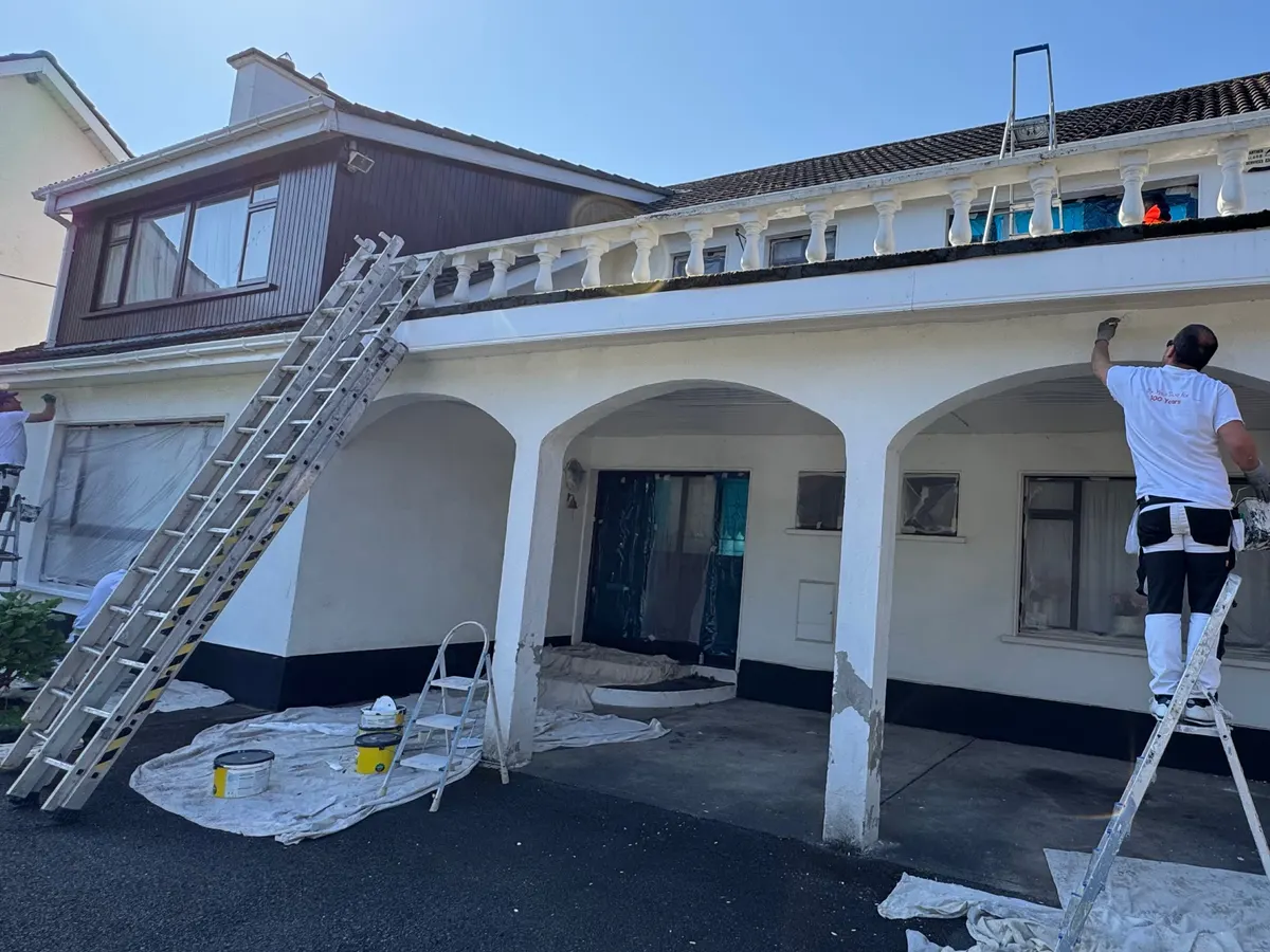 Painter on a stepladder painting the arched front porch of a detached house in Castleknock, Dublin 15