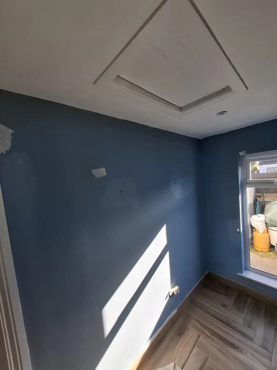 Freshly painted deep blue feature wall and ceiling in a Dublin bedroom